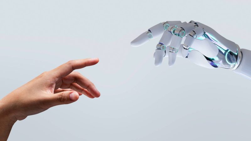 Mano humana y mano robótica conectándose, símbolo de la integración entre inteligencia artificial y estrategia de marketing digital en 2026.